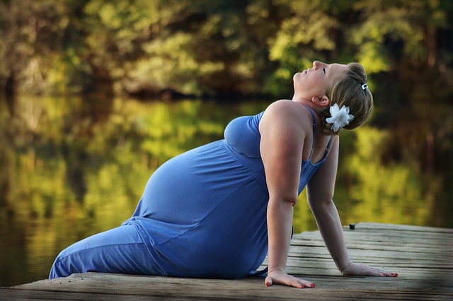 אישה בהריון יושבת על מזח ליד המים